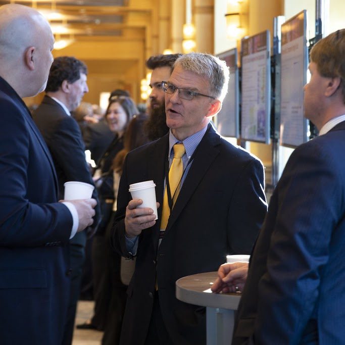 Professionals networking with coffee in hand at a NEAT-hosted event